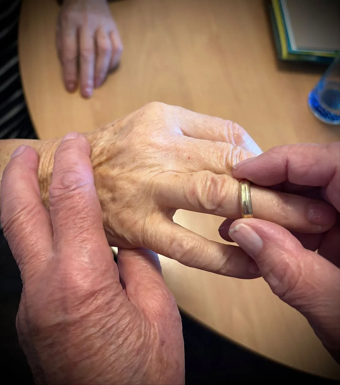 Hände einer älteren Dame, an deren Finger ein goldener Ring wieder aufgesteckt wird
